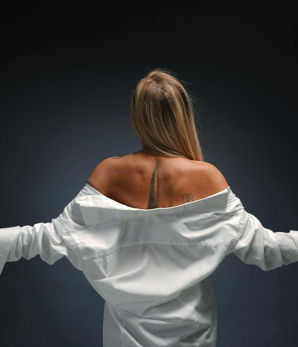 Woman in a peaceful yoga pose against a dark background with pink light accents.